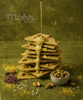Stack of chocolate bars with a drizzle of chocolate being poured over them, on a green textured background.